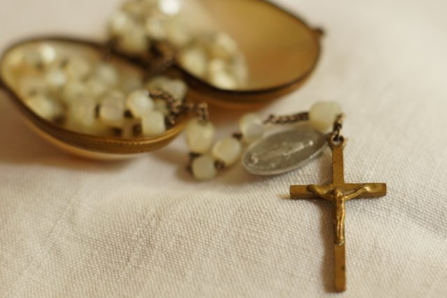 Rosenkranz mit Messingkreuz, im Hintergrund Perlmuttdose