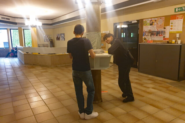 2 Jugendliche an einem Säulentisch stehend, in Arbeit vertieft