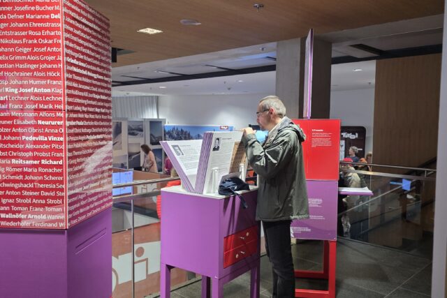 rot-violette Ausstellungselemente mit Person vor einem Infostand