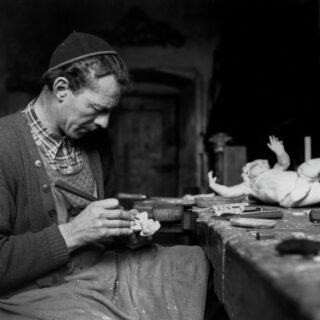 Mann mit Schnitzeisen an einem Werktisch