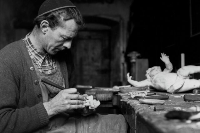 Mann mit Schnitzeisen an einem Werktisch